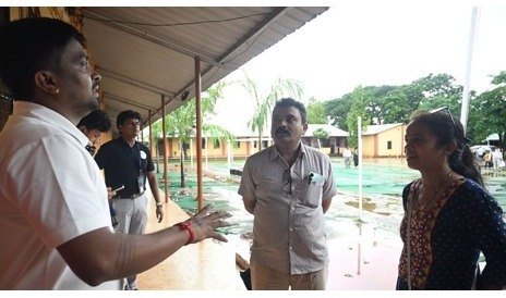 A presenter speaking with adults in a covered corridor